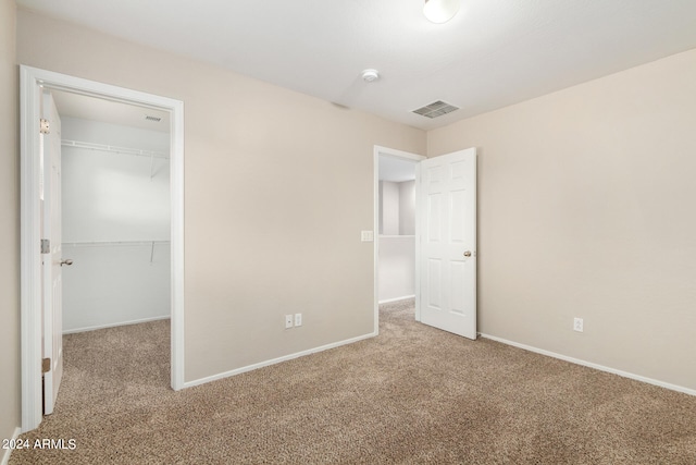 unfurnished bedroom featuring a closet, a walk in closet, and carpet floors