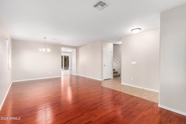 spare room featuring an inviting chandelier and hardwood / wood-style flooring