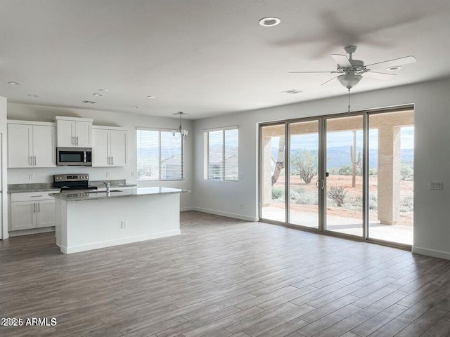 kitchen with stainless steel appliances, white cabinets, a center island with sink, and wood finished floors