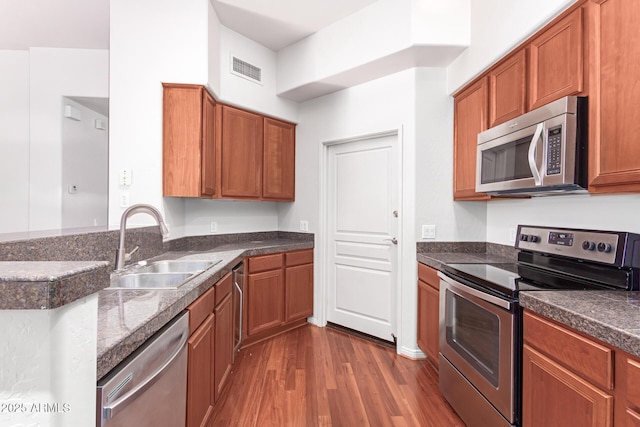 kitchen featuring sink, dark wood-type flooring, stainless steel appliances, and kitchen peninsula