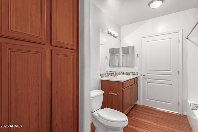 bathroom with hardwood / wood-style flooring, vanity, toilet, and backsplash