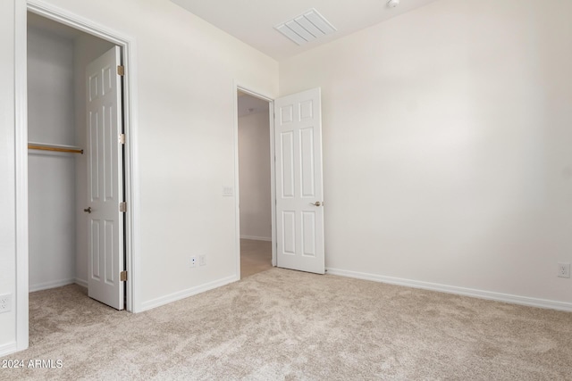 unfurnished bedroom with light carpet and a closet