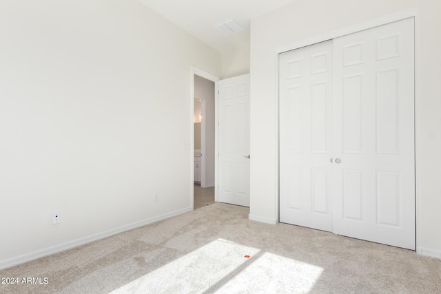 unfurnished bedroom with light colored carpet and a closet