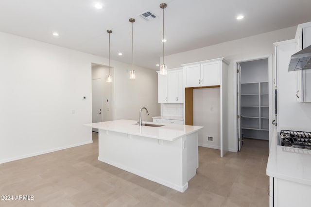 kitchen featuring tasteful backsplash, sink, pendant lighting, white cabinets, and an island with sink