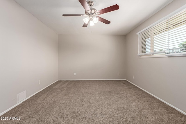 carpeted empty room with baseboards, visible vents, and ceiling fan
