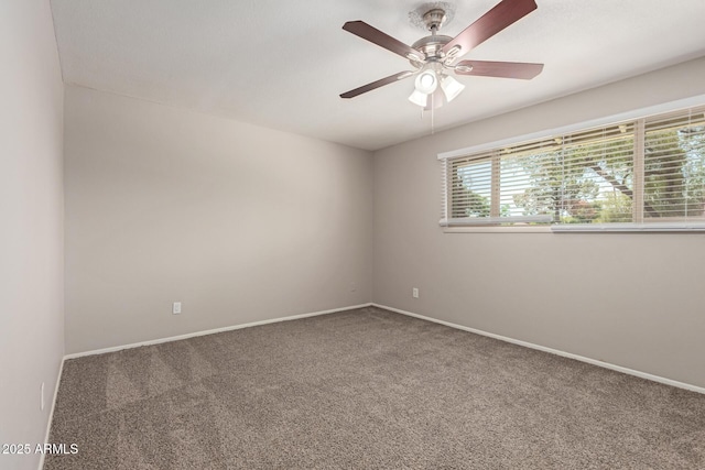 carpeted spare room with ceiling fan and baseboards