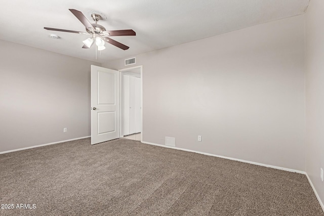 carpeted empty room featuring baseboards, visible vents, and a ceiling fan