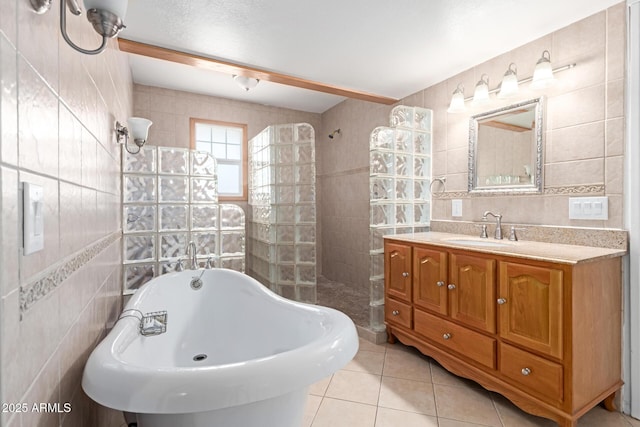 bathroom featuring tile walls, a sink, a walk in shower, tile patterned floors, and a soaking tub