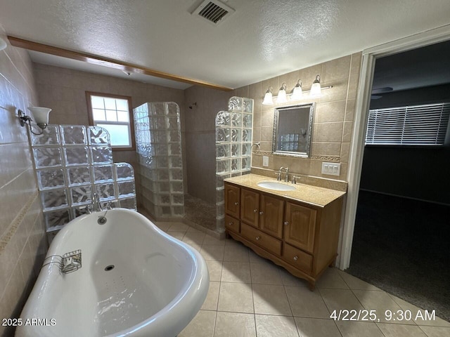 full bathroom featuring a freestanding bath, tile walls, a textured ceiling, and walk in shower