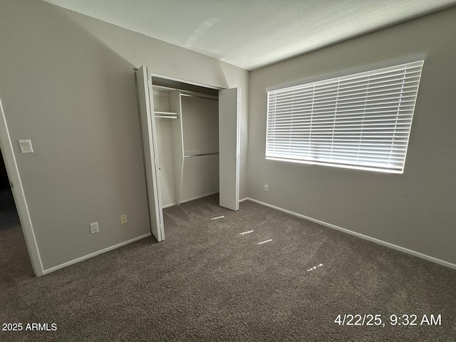 unfurnished bedroom featuring baseboards, carpet floors, and a closet