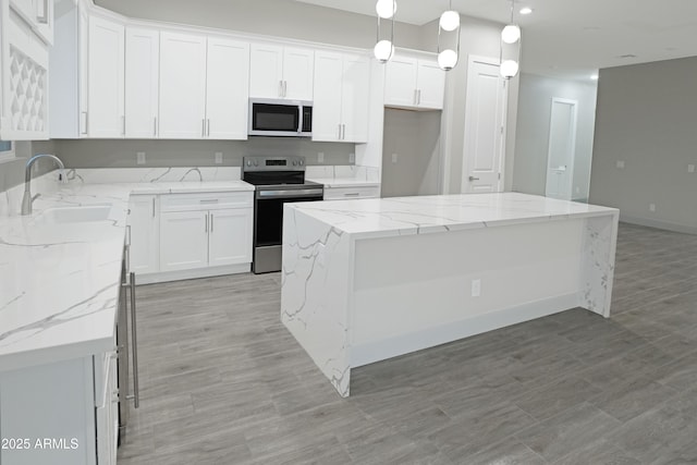 kitchen featuring a sink, stainless steel electric range oven, a center island, and white cabinetry