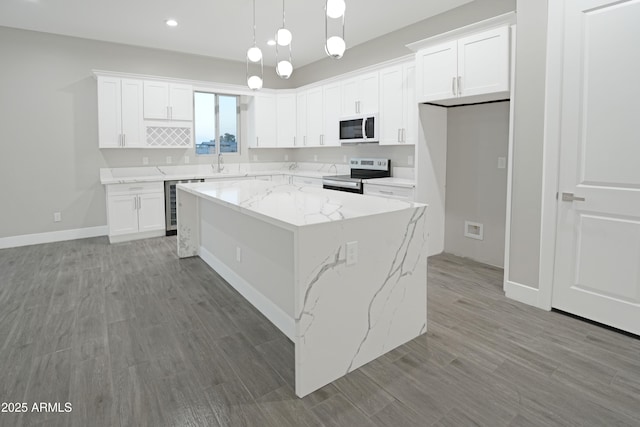 kitchen featuring white microwave, a center island, wine cooler, electric range, and a sink