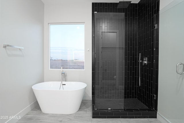 full bathroom with baseboards, a freestanding bath, and a shower stall