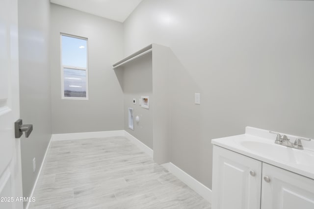 washroom with baseboards, cabinet space, a sink, washer hookup, and electric dryer hookup