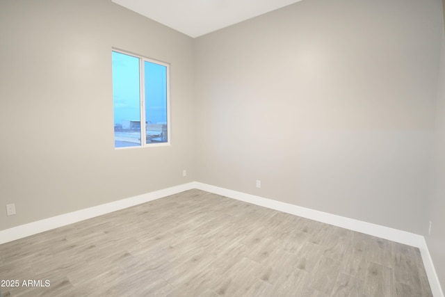 spare room featuring baseboards and light wood-style floors