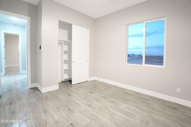 unfurnished bedroom featuring a closet, light wood-style flooring, and baseboards