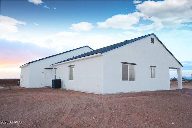 property exterior at dusk featuring stucco siding and central AC unit