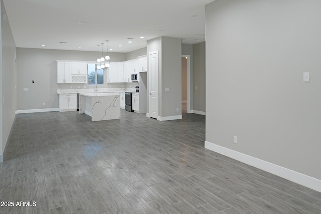 unfurnished living room featuring a sink, recessed lighting, baseboards, and wood finished floors