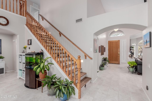 entryway featuring visible vents, arched walkways, and a towering ceiling