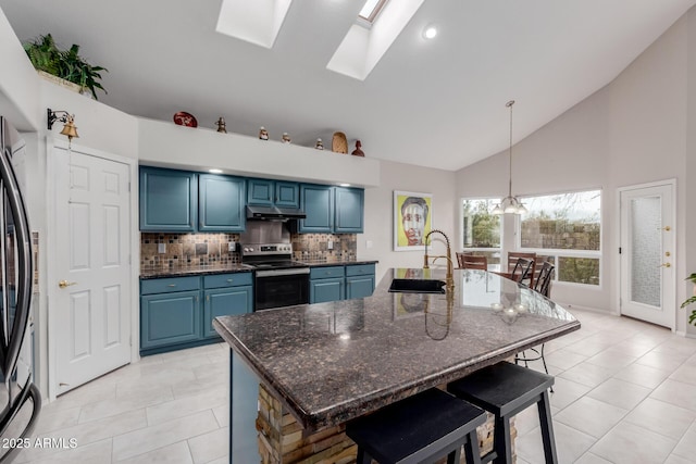 kitchen with a breakfast bar area, a sink, under cabinet range hood, appliances with stainless steel finishes, and blue cabinets