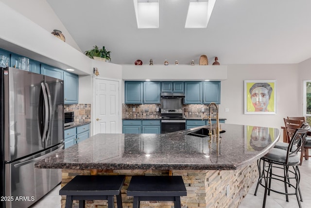 kitchen with blue cabinetry, appliances with stainless steel finishes, lofted ceiling, and a sink