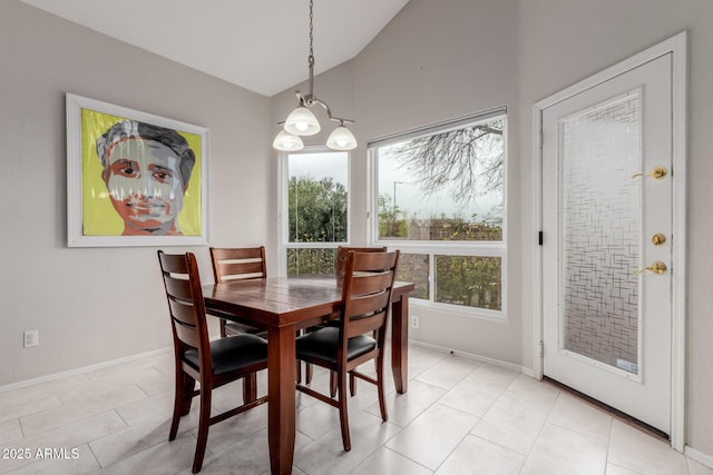 dining room with light tile patterned floors, baseboards, and vaulted ceiling