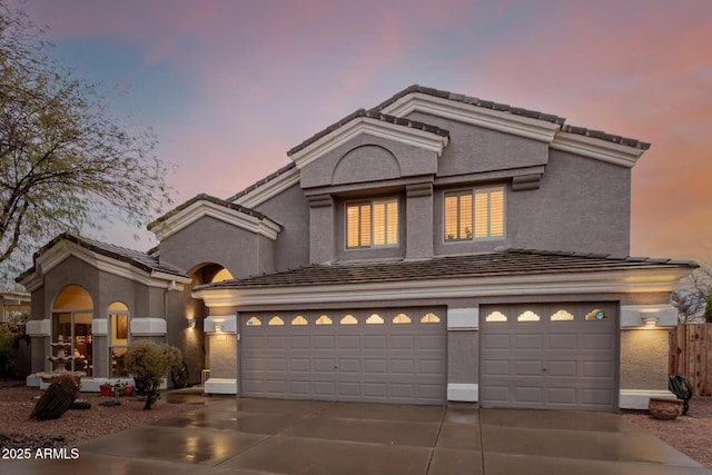 mediterranean / spanish-style home with stucco siding, a garage, and concrete driveway