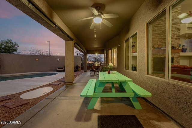 patio terrace at dusk with a fenced backyard, a fenced in pool, outdoor dining area, and ceiling fan