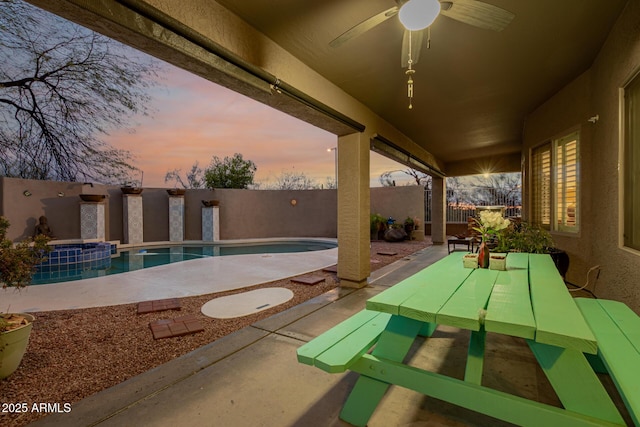 patio terrace at dusk with a fenced in pool, a ceiling fan, and a fenced backyard