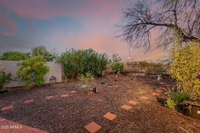 yard at dusk featuring a fenced backyard