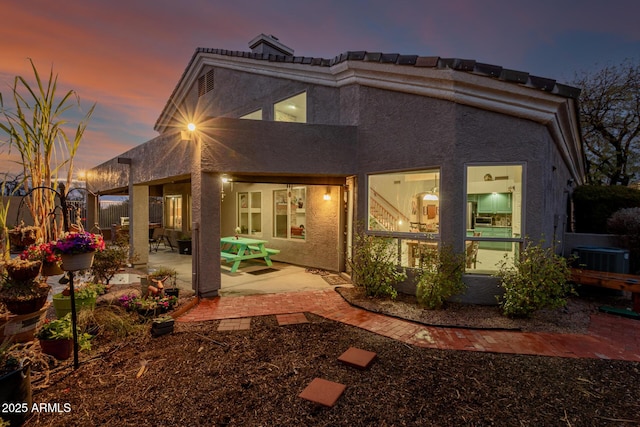 back of property with a patio, cooling unit, and stucco siding