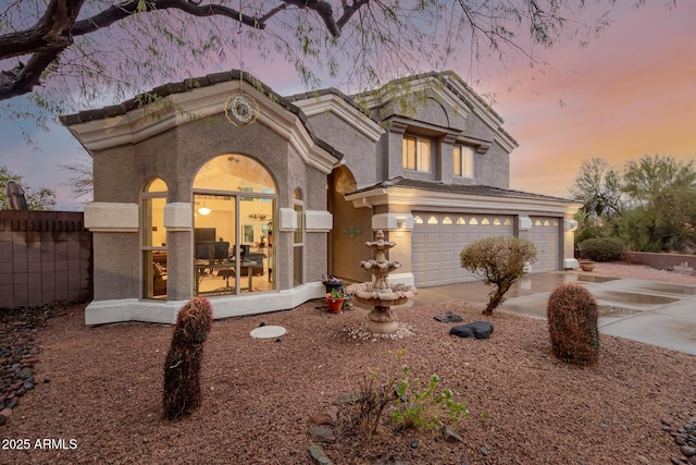 view of front of home with a garage, fence, driveway, and stucco siding