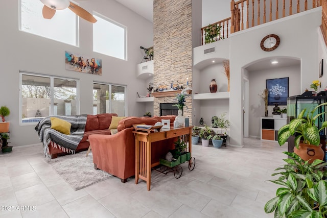 living area with visible vents, baseboards, light tile patterned floors, a fireplace, and a ceiling fan