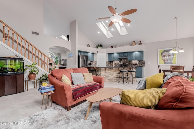 living room with visible vents, stairs, ceiling fan with notable chandelier, a skylight, and arched walkways