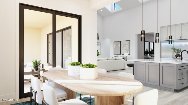 dining area featuring a skylight, high vaulted ceiling, and light hardwood / wood-style flooring