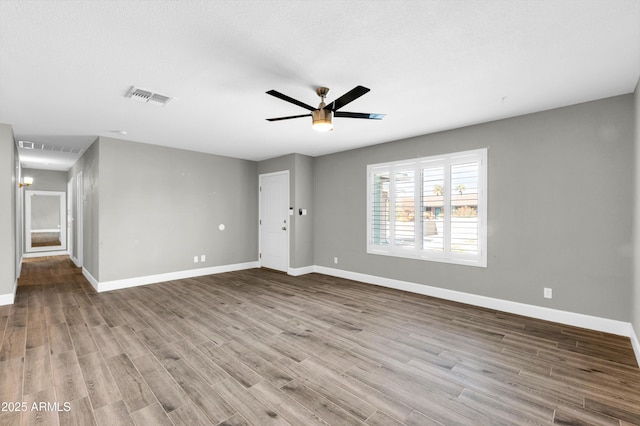 interior space with baseboards, ceiling fan, visible vents, and wood finished floors