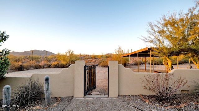 exterior space featuring a mountain view, fence, stucco siding, and a gate