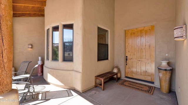 view of exterior entry featuring stucco siding and a patio area