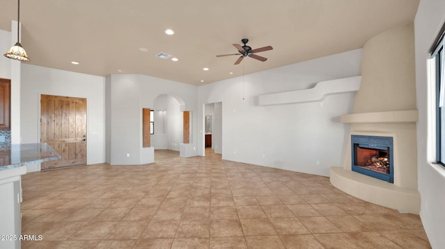 unfurnished living room featuring visible vents, recessed lighting, a fireplace, arched walkways, and a ceiling fan