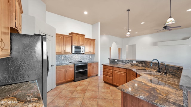 kitchen with light tile patterned floors, arched walkways, a sink, decorative backsplash, and appliances with stainless steel finishes