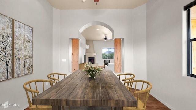 dining area with arched walkways, baseboards, ceiling fan, and wood finished floors