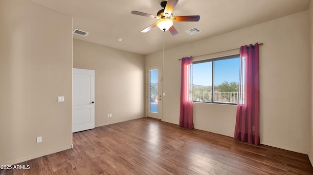 unfurnished room with a ceiling fan, wood finished floors, visible vents, and baseboards