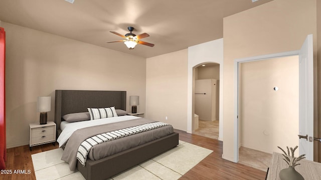 bedroom with ceiling fan, arched walkways, and wood finished floors