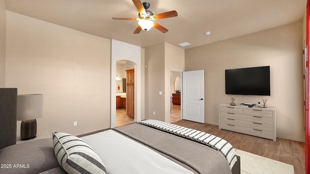 bedroom with visible vents, baseboards, arched walkways, light wood-type flooring, and connected bathroom