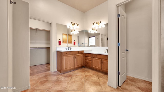 bathroom featuring double vanity, baseboards, tile patterned floors, and a sink