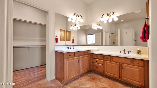 full bathroom with double vanity, a spacious closet, and a sink