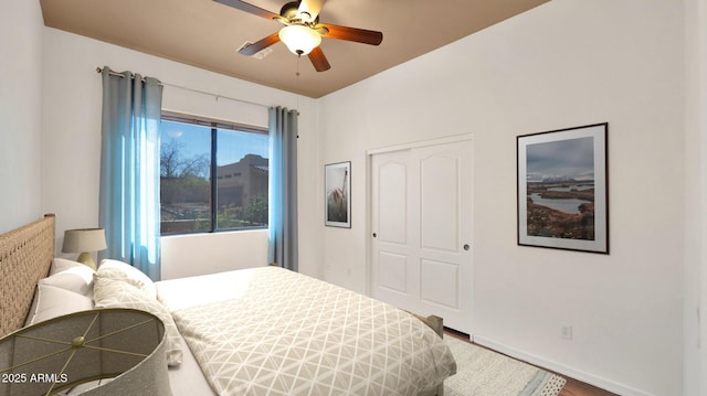 bedroom with a closet, a ceiling fan, baseboards, and wood finished floors