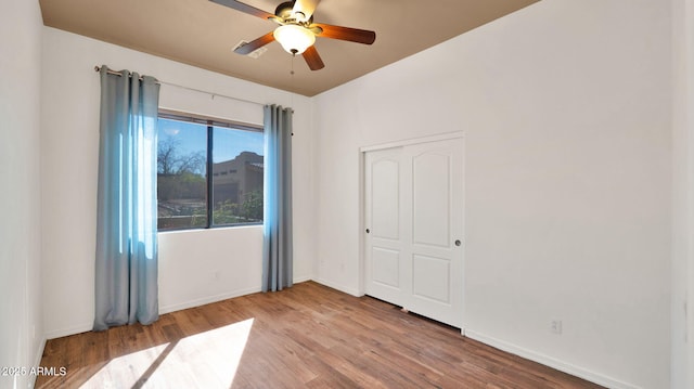 unfurnished bedroom featuring a ceiling fan, wood finished floors, baseboards, and a closet