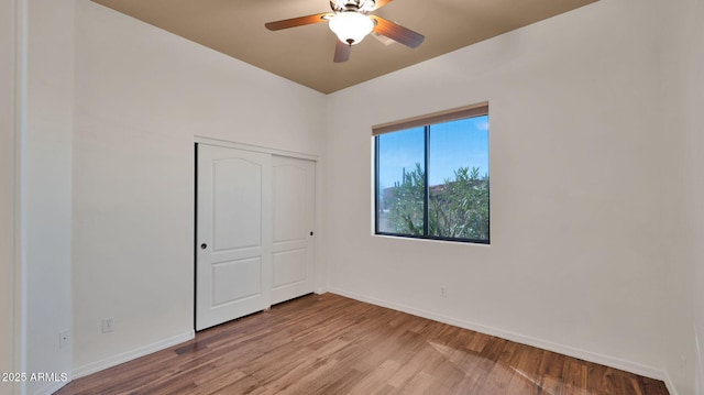 unfurnished bedroom with a ceiling fan, wood finished floors, baseboards, and a closet