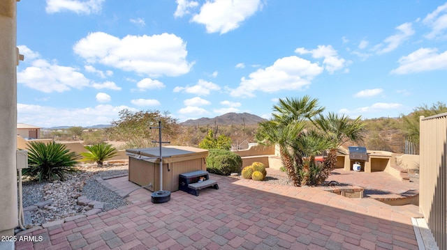 view of patio / terrace featuring a mountain view, a hot tub, and exterior kitchen